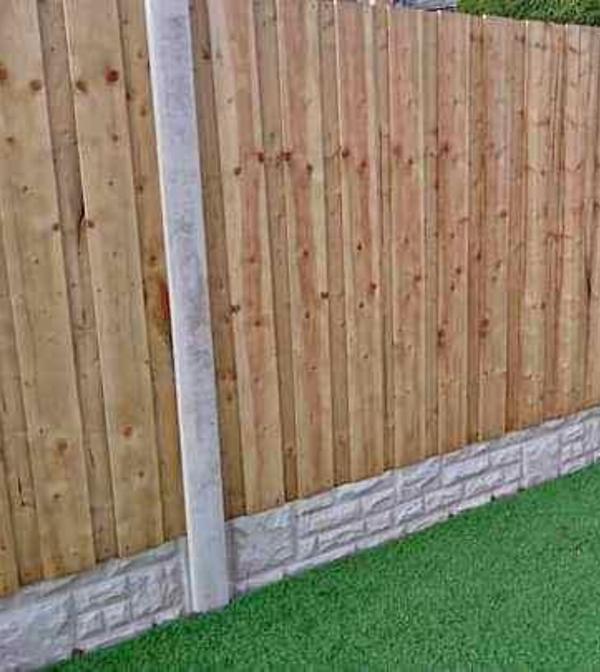 Close view of new closeboard fence panels meeting a concrete post above a rock-faced gravel board