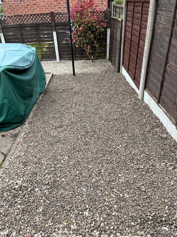 A side passage finished with evenly spread decorative gravel between fence panels