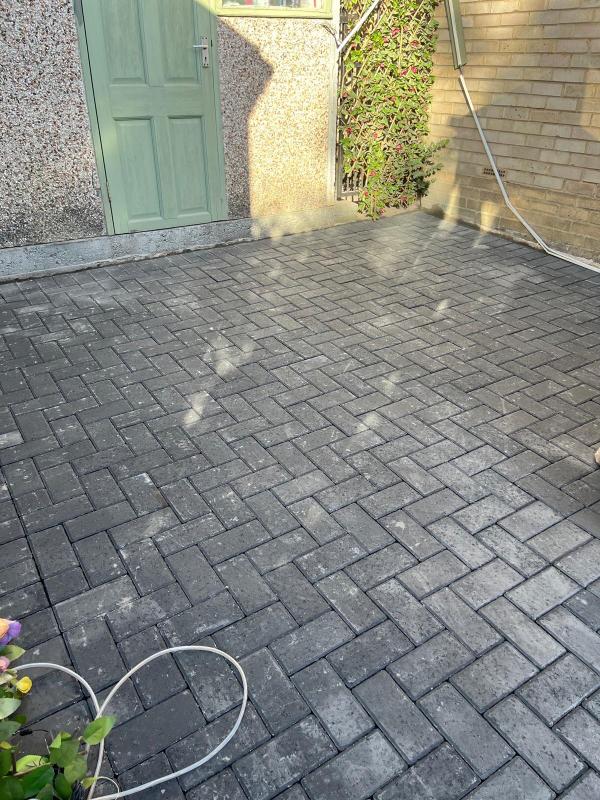 Charcoal block paving laid in a herringbone pattern across a rear courtyard
