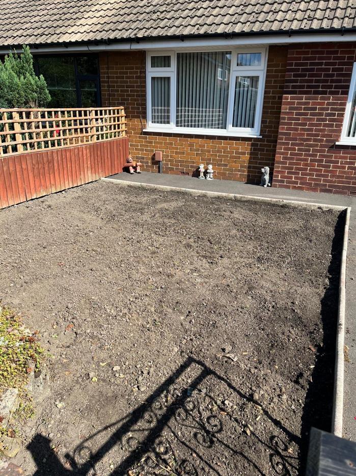 Bare, stony soil across a front garden after the old surface was stripped out